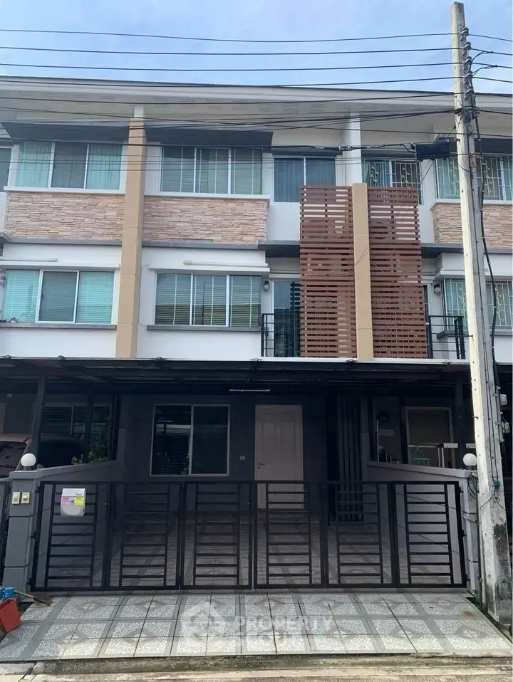 Modern three-story townhouse with gated entrance and contemporary facade.