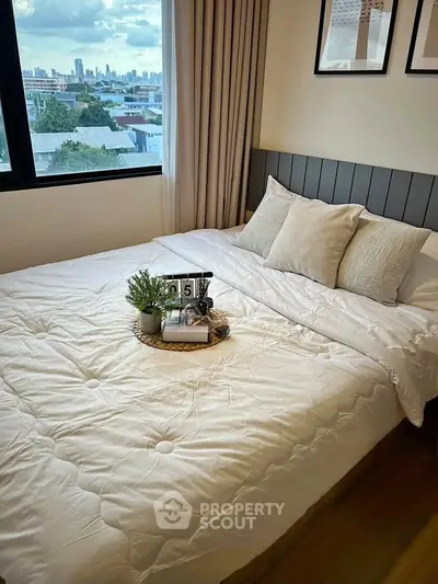 Cozy bedroom with city view, featuring a neatly made bed and decorative accents, perfect for urban living.