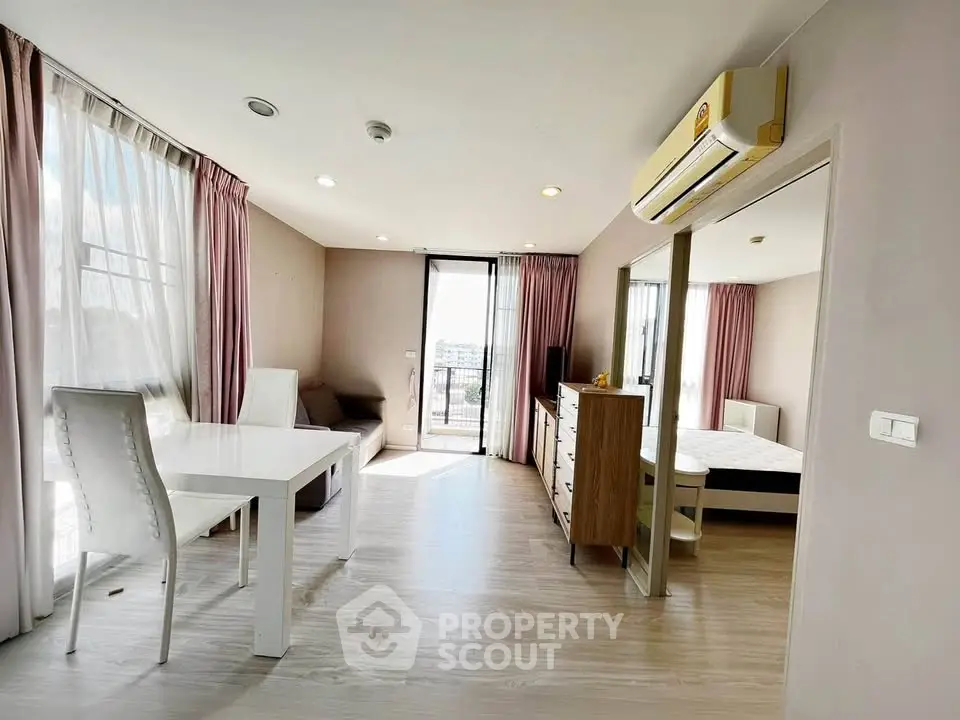 Spacious modern living room with dining area and bedroom access, featuring large windows and natural light.