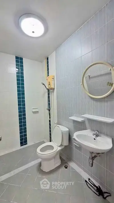 Modern bathroom with sleek design, featuring a shower, toilet, and sink in a tiled setting.
