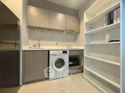 Modern kitchen with washing machine and sleek cabinetry in a compact layout.