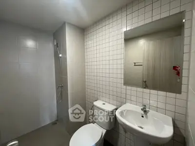 Modern bathroom with sleek fixtures and minimalist design, featuring a shower, toilet, and sink.