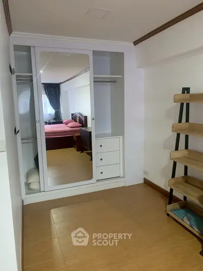 Spacious bedroom with mirrored wardrobe and wooden flooring, ideal for modern living.
