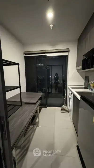 Modern kitchen with sleek appliances and city view through glass doors.