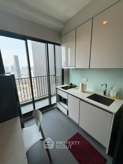 Modern kitchen with city view, sleek cabinetry, and compact design in high-rise apartment.