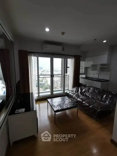 Modern living room with large window and city view, featuring sleek furniture and wooden flooring.