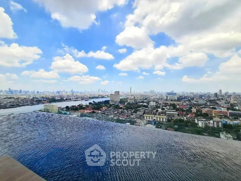 Stunning rooftop infinity pool with panoramic city skyline view under a bright blue sky.