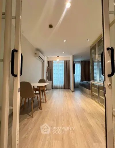 Modern living room with wooden flooring and large windows in a stylish apartment.