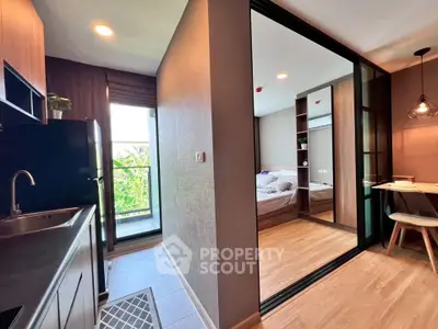 Modern apartment interior with sleek kitchen and cozy bedroom, featuring stylish lighting and wooden flooring.