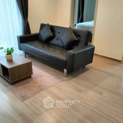 Modern living room with sleek black sofa and wooden coffee table, featuring elegant decor and natural light.