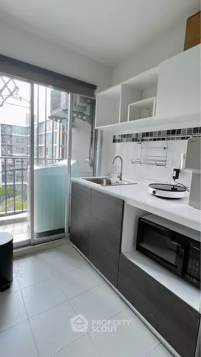 Modern kitchen with balcony view, featuring sleek cabinets and appliances in a compact layout.
