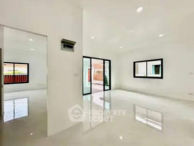 Spacious modern living room with large windows and glossy floors in a bright home.