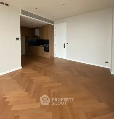 Spacious modern living room with elegant wooden flooring and open kitchen layout.