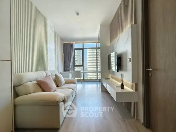 Modern living room with stylish decor and large windows offering a city view.