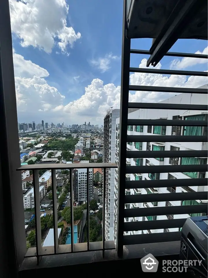 Stunning cityscape view from high-rise balcony with modern architecture and lush greenery.