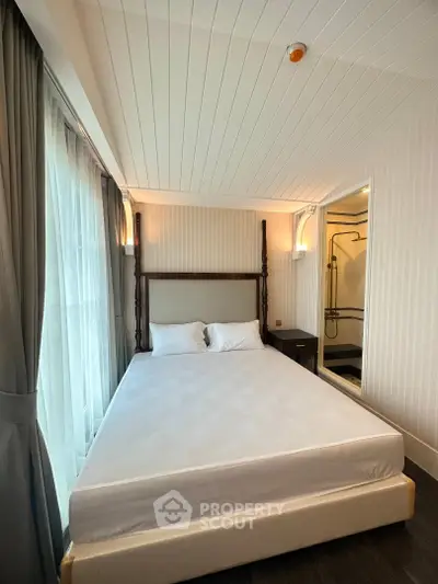 Elegant bedroom with large windows and modern decor, featuring a comfortable bed and stylish lighting.