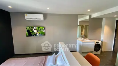 Modern bedroom with sleek design, featuring a wall-mounted TV, air conditioning, and in-room washing machine.