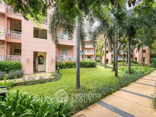 Charming residential building with lush garden and palm trees, offering serene living environment.