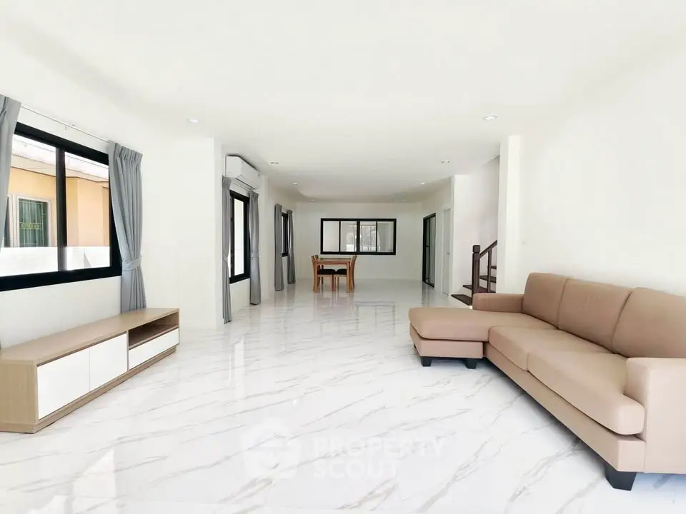 Spacious modern living room with elegant marble flooring and stylish furniture in a bright open layout.