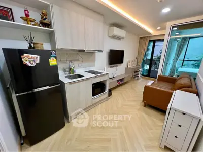 Modern open-layout living room with kitchen, featuring sleek appliances and cozy seating area.
