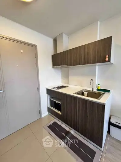 Modern compact kitchen with sleek cabinetry and built-in appliances in a stylish apartment.