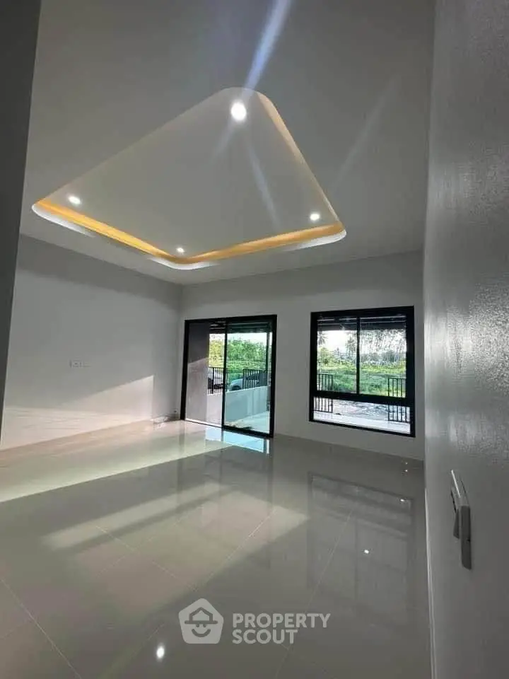 Spacious modern living room with large windows and elegant ceiling lighting.