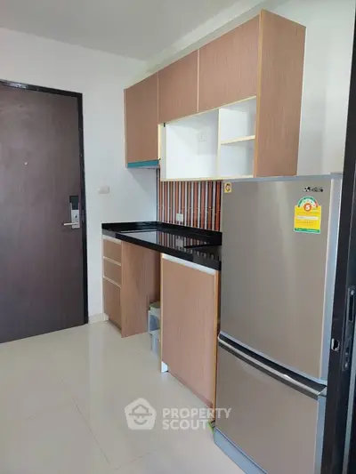 Modern kitchen with sleek cabinetry and stainless steel fridge in a compact layout.