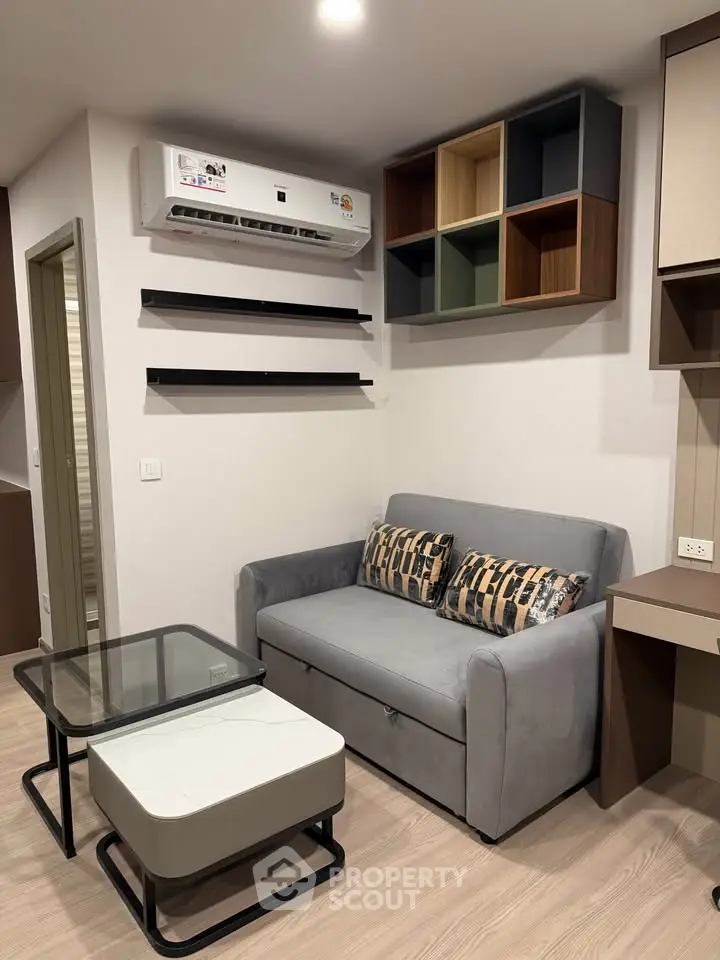 Modern living room with stylish sofa, wall-mounted shelves, and air conditioning unit.