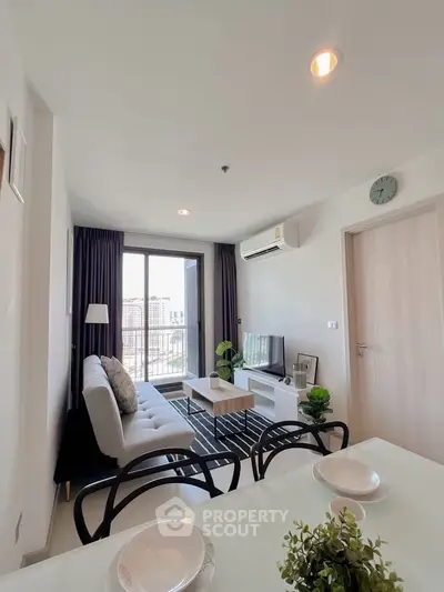 Modern living room with stylish decor and city view, featuring a cozy sofa and sleek TV setup.