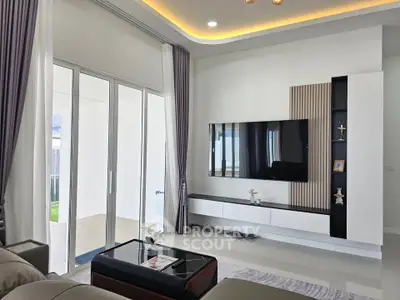 Modern living room with sleek TV setup and large sliding glass doors leading to patio.