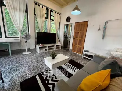 Charming living room with high ceilings, large windows, and modern decor in a cozy home.