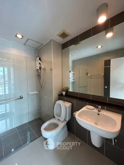 Modern bathroom with sleek fixtures and large mirror in contemporary apartment.