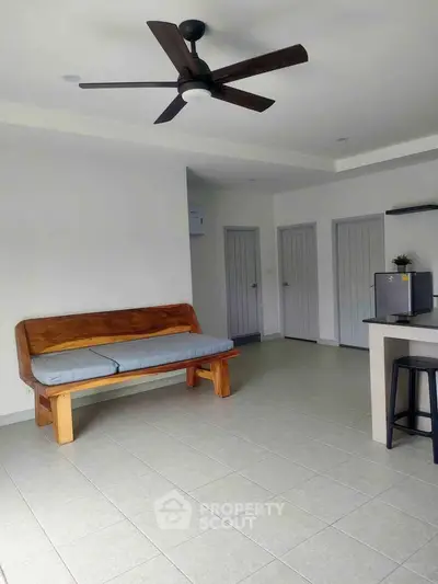 Spacious living room with modern ceiling fan and wooden bench, ideal for relaxation and comfort.
