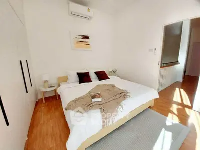 Bright and cozy bedroom with modern decor and wooden flooring, perfect for relaxation.