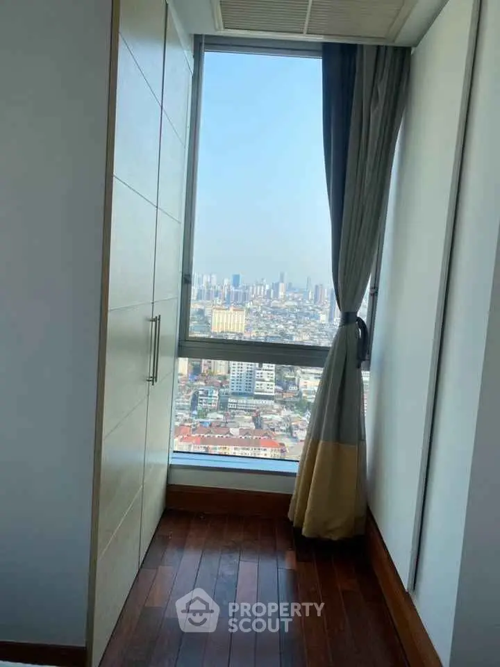 Stunning city view from a high-rise apartment window with elegant curtains.