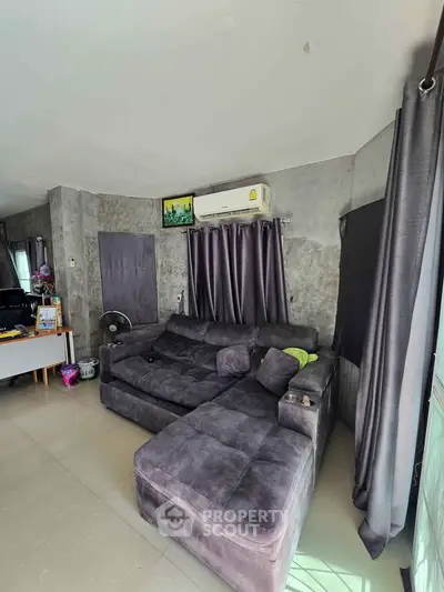 Spacious living room with modern gray sectional sofa and air conditioning, perfect for relaxation.