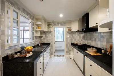 Spacious kitchen with modern black countertops and city view window