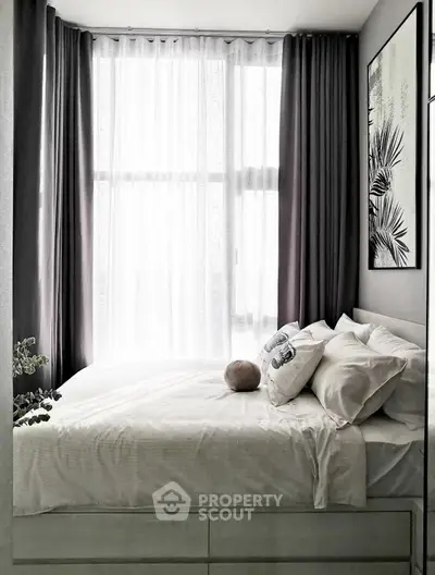 Cozy bedroom with large window and elegant decor, perfect for relaxation.