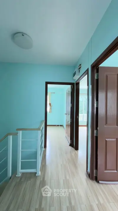 Bright hallway with wooden flooring and open doors leading to spacious rooms.