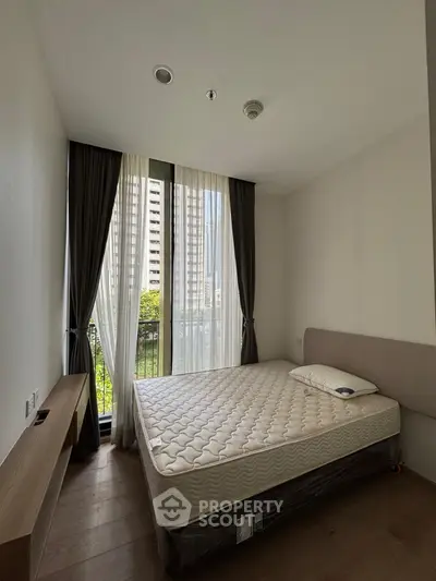 Modern bedroom with large window and minimalist design in urban apartment.