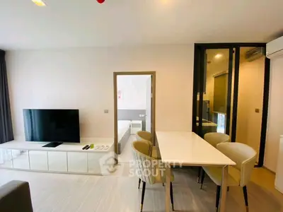 Modern living room with dining area and TV, open to bedroom view.