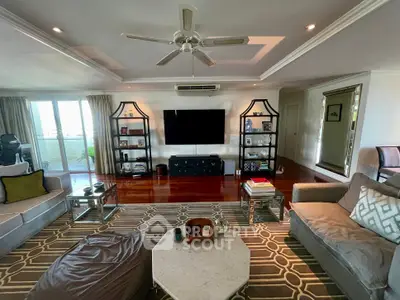 Spacious living room with modern decor and large TV, featuring elegant shelving and plush seating.