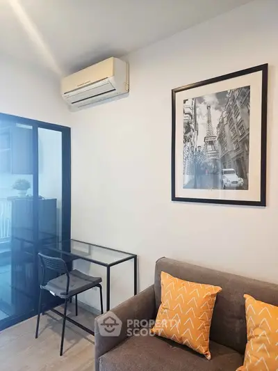 Modern living room with stylish decor and air conditioning, featuring a framed cityscape art piece.