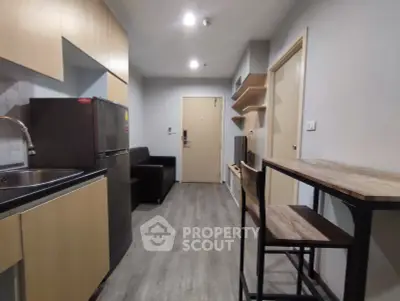 Modern apartment interior with kitchen and living area, featuring sleek cabinetry and contemporary furnishings.
