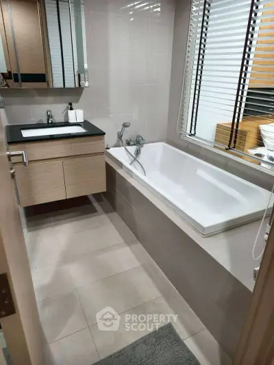 Modern bathroom with sleek design featuring a bathtub and stylish vanity.