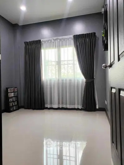 Spacious room with large window and elegant curtains, perfect for a cozy living space.