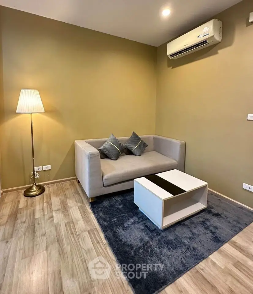 Cozy living room with modern sofa, stylish lamp, and air conditioning unit.