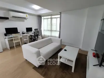 Modern living room with white sofa, work desk, and natural light
