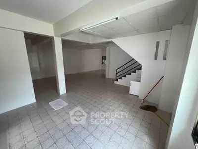 Spacious open-plan interior with tiled flooring and staircase, ideal for versatile use.