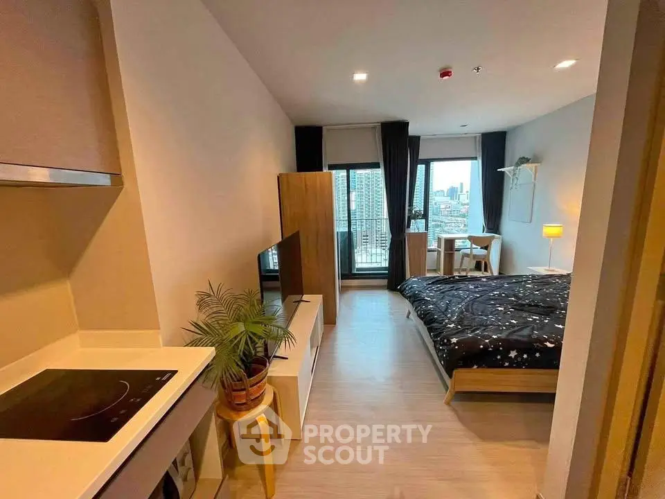 Modern studio apartment with city view, featuring cozy bedroom and compact kitchen area.